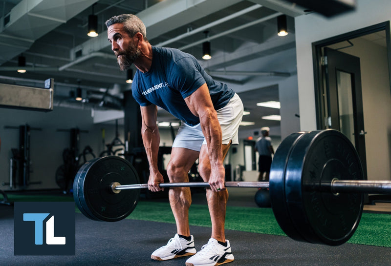 Lower back workouts: Man lifts a barbell in a deserted building