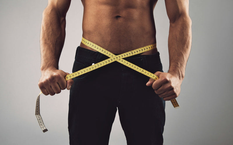 Fit man measuring his body with tape measure after easy weight loss