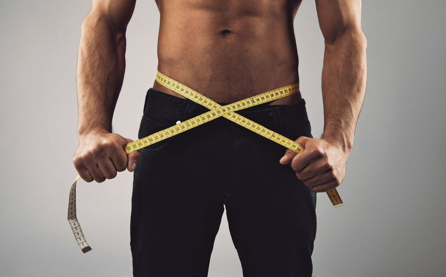 Fit man measuring his body with tape measure after easy weight loss