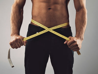 Fit man measuring his body with tape measure after easy weight loss