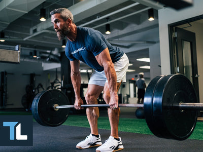 Lower back workouts: Man lifts a barbell in a deserted building
